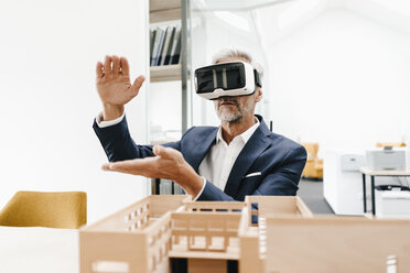 Reifer Geschäftsmann mit Architekturmodell im Büro mit VR-Brille - KNSF02154