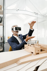Reifer Geschäftsmann mit Architekturmodell im Büro mit VR-Brille - KNSF02156