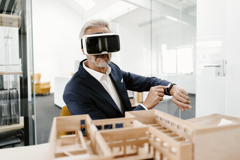 Reifer Geschäftsmann mit Architekturmodell im Büro mit VR-Brille - KNSF02160