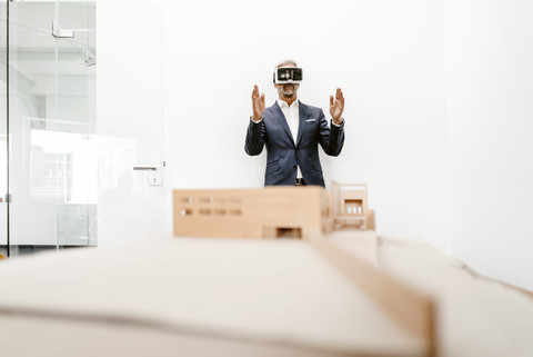 Reifer Geschäftsmann mit Architekturmodell im Büro mit VR-Brille, lizenzfreies Stockfoto