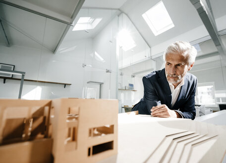 Älterer Geschäftsmann, der ein architektonisches Modell im Büro untersucht - KNSF02172