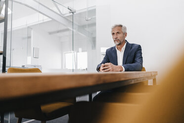 Älterer Geschäftsmann sitzt am Konferenztisch im Büro - KNSF02177