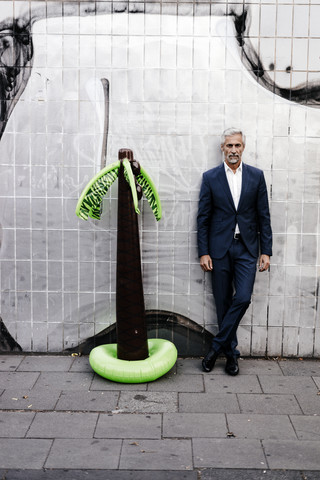 Älterer Geschäftsmann im Freien mit aufblasbarer Palme, lizenzfreies Stockfoto