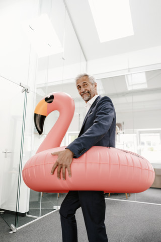 Businessman in office with inflatable flamingo stock photo