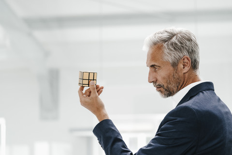 Mature businessman in office examining Rubik's Cube stock photo
