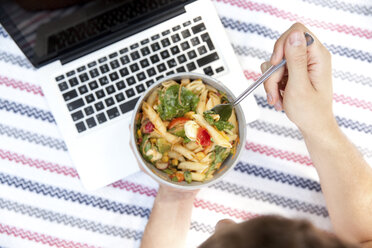 Man eating noodle salad on blanket in a park, partial view - MFRF00931