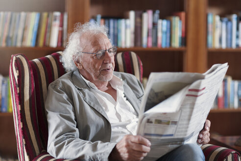 Älterer Mann sitzt in der Bibliothek und liest Zeitung - ZEF14199