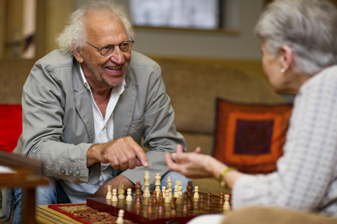 Senior man and woman playing chess in retirement home stock photo
