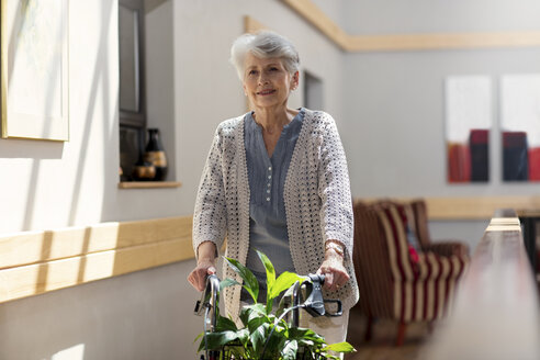 Ältere Frau im Altersheim, die eine Gehhilfe auf Rädern schiebt - ZEF14213