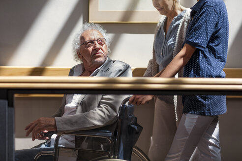 Altenpflegerin hilft älterem Mann und älterer Frau beim Gehen im Flur - ZEF14219