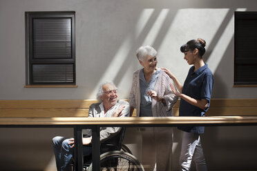 Altenpflegerin hilft älterem Mann und älterer Frau beim Gehen im Flur - ZEF14220