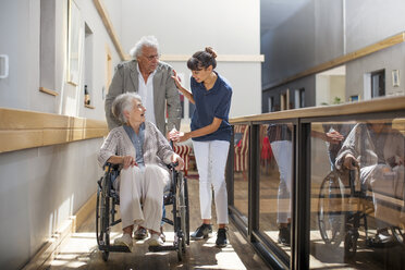 Altenpflegerin hilft älterem Mann und älterer Frau beim Gehen im Flur - ZEF14222