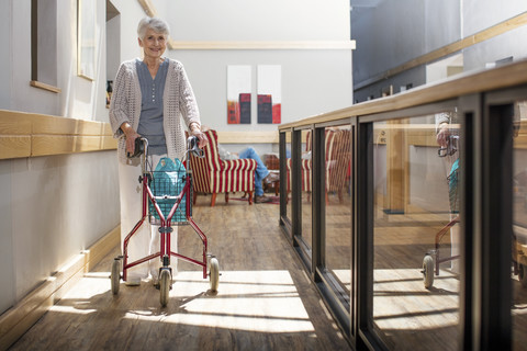 Senior woman in retirement home pushing wheeled walker stock photo