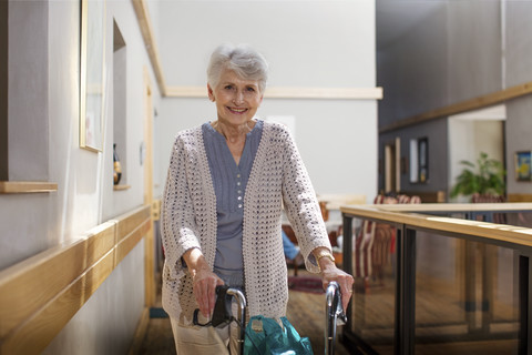 Senior woman in retirement home pushing wheeled walker stock photo