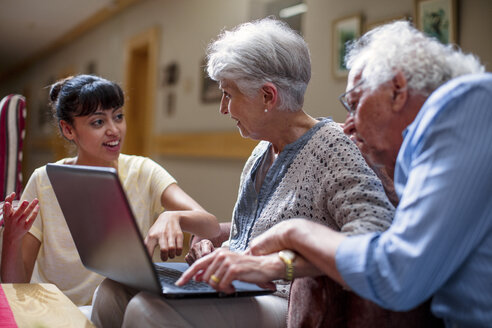 Nurse teaching seniors in retirement home, how to use laptop - ZEF14233