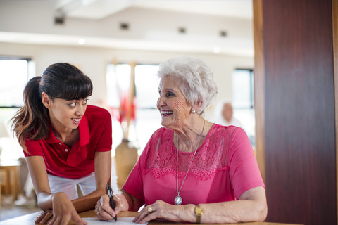 Senior woman signing a contract, nurse helping her stock photo