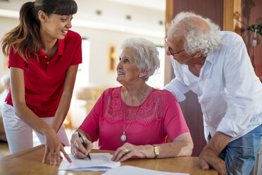 Senior woman signing a contract, nurse and senior man helping her - ZEF14242