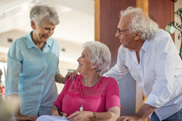 Senior woman signing a contract, friends reassuring her - ZEF14244