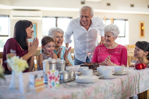 Großeltern feiern mit ihrer Enkelin einen Geburtstag, lizenzfreies Stockfoto