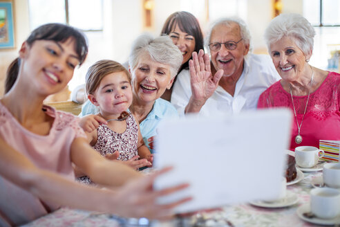 Grandparents celebrating a birthday with their granddaughter, taking picture with digital tablet - ZEF14265