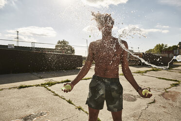 Young couple throwing water bags in summer - SUF00258