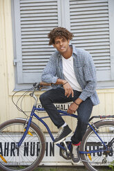 Young man sitting on bicycle, looking at camera - SUF00276