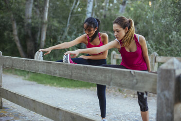 Two active women stretching at a brick wall - JPF00256