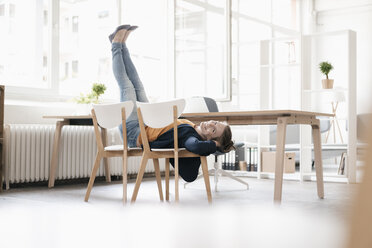 Woman doing gymnastics on chairs in a loft - KNSF02237