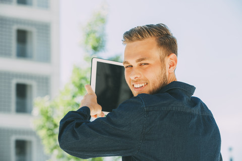 Porträt eines lächelnden jungen Mannes, der ein Foto mit einem Tablet macht, lizenzfreies Stockfoto