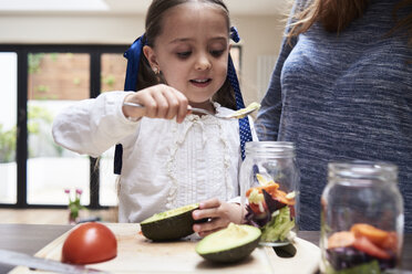 Porträt eines kleinen Mädchens, das mit seiner Mutter in der Küche einen gesunden Salat zubereitet - IGGF00003