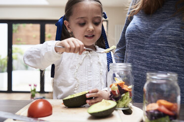 Portrait of little girl preparing healthy salad with her mother in the kitchen - IGGF00003