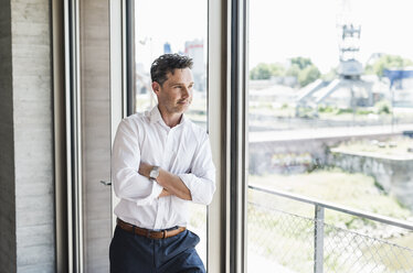 Portrait of confident businessman looking through window - UUF11215