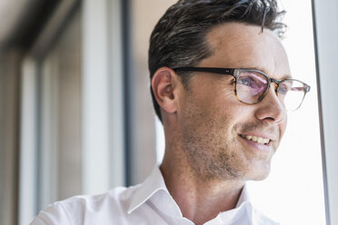 Portrait of confident businessman looking through window - UUF11218