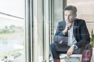 Portrait of pensive businessman looking through window - UUF11233