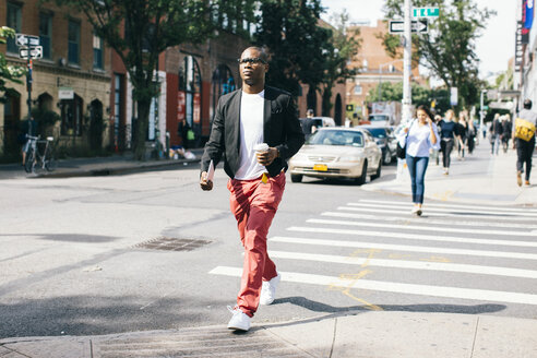 USA, NYC, Brooklyn, Man walking in the street, holding cup of coffee - JUBF00236