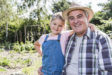 Portrait of smiling grandfather and granddaughter in the garden stock photo