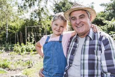 Portrait of smiling grandfather and granddaughter in the garden - UUF11319