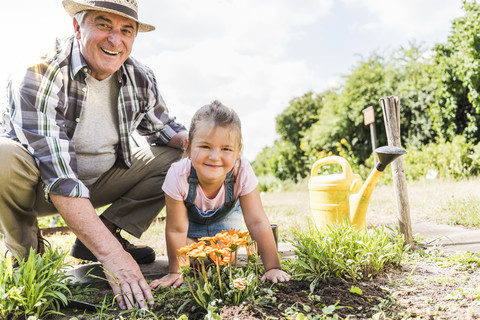 Porträt eines glücklichen Großvaters und einer Enkelin im Garten, lizenzfreies Stockfoto