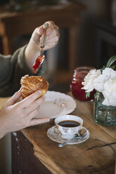 Nahaufnahme einer Frau, die hausgemachte Croissants mit Marmelade probiert - ALBF00148