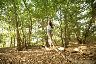 Young woman in forest balancing on a log - MFRF00955