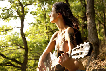 Junge Frau spielt Gitarre im Wald - MFRF00963