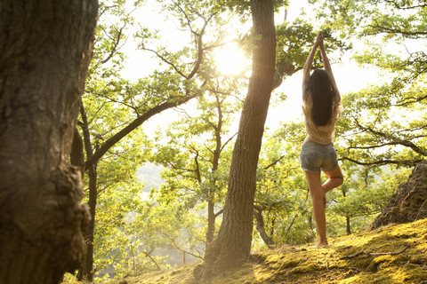 Junge Frau im Wald übt Yoga, lizenzfreies Stockfoto