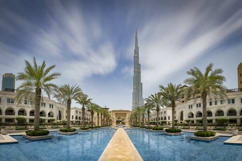 Vereinigte Arabische Emirate, Dubai, Burj Khalifa mit Häusern im traditionellen Stil um ein Wasserbecken mit Palmen, lizenzfreies Stockfoto