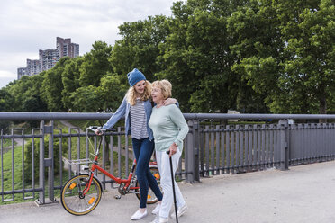 Grandmother and granddaughter strolling on a bridge - UUF11362