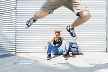 Young woman watching her boyfriend jumping in the air - FMOF00296