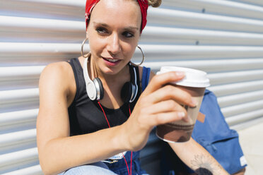 Porträt einer jungen Frau mit Kopfhörern und Kaffee zum Mitnehmen - FMOF00297