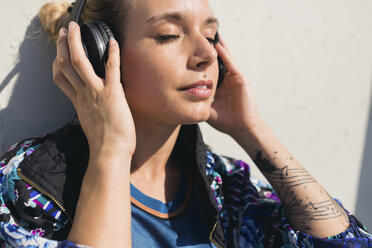 Portrait of young woman with eyes closed listening music with headphones - FMOF00316