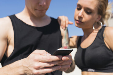 Young couple looking at cell phone, close-up - FMOF00320