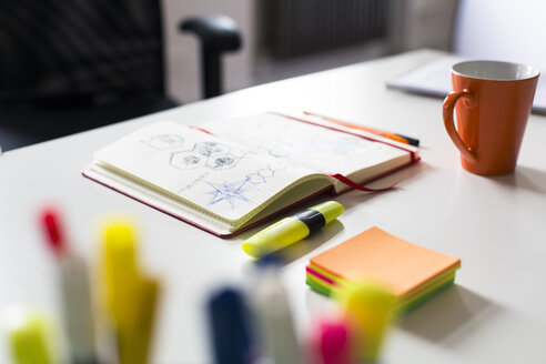 Notizbuch mit Skizze, Textmarker und Tasse Kaffee auf dem Schreibtisch im Büro - FKF02460