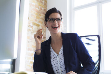 Laughing businesswoman at desk in office - FKF02486